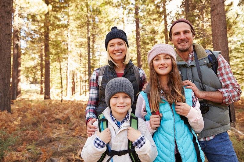 Familj med en mamma, pappa och två barn på utflykt i skogen på hösten.