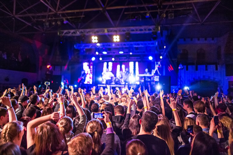 En stor publik står vänd mot en upplyst scen med livemusik.