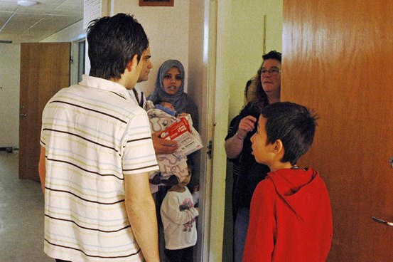 En grupp asylsökande kvinnor och barn samtalar i en korridor