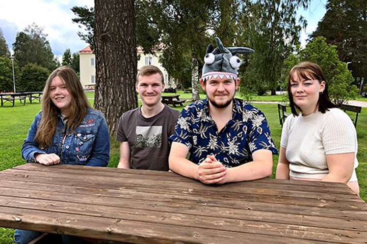 Fyra deltagare sitter vid ett bord på skolområdet.