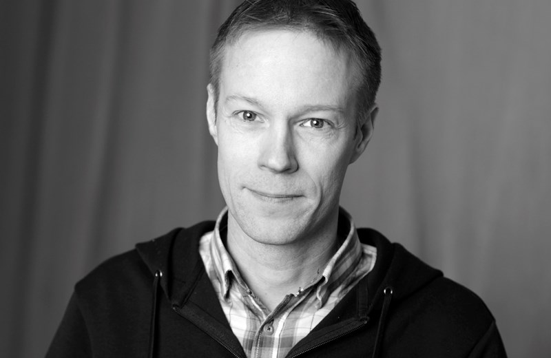 En svartvit bild på en man som tittar in i kameran