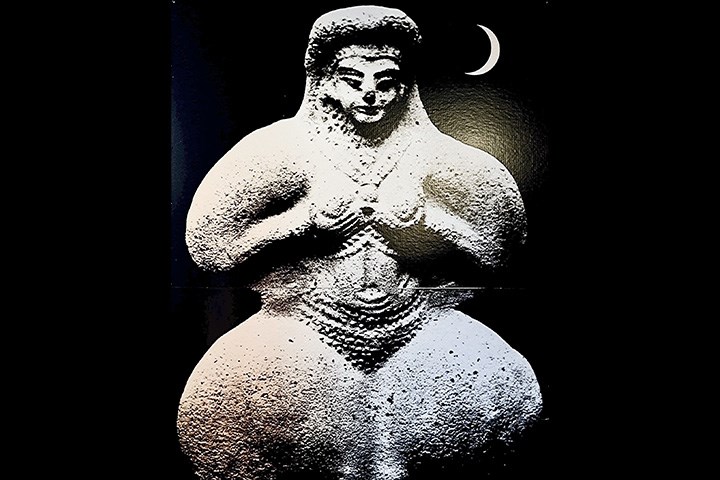 En mytologisk kvinnofigur i sten mot en svart bakgrund.