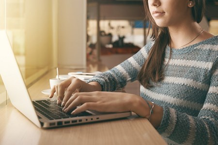 En kvinna sitter och skriver på en bärbar dator