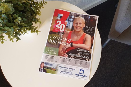 Ett tidningsomslag på ett bord med en kvinna som står i ett gym med rubriken Charlotte tog steget intill.