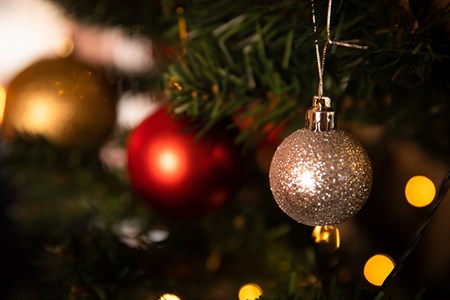 En närbild på en glittrig julkula i guld som hänger i en julgran.