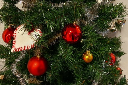 Närbild på röda och guldfärgade julkulor och ett vitt hjärta i en julgran i plast.