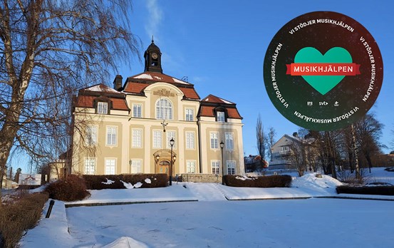 Skolans fasad i ett vinterlandskap och Musikhjälpens logotyp bredvid.