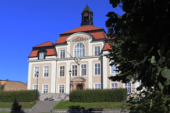 Skolans fasad omringad av ett grönområde och en blå himmel.