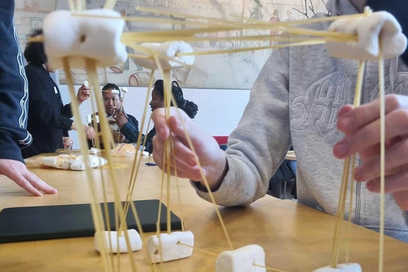 Några personer bygger ett ron av spaghetti och marshmallows.