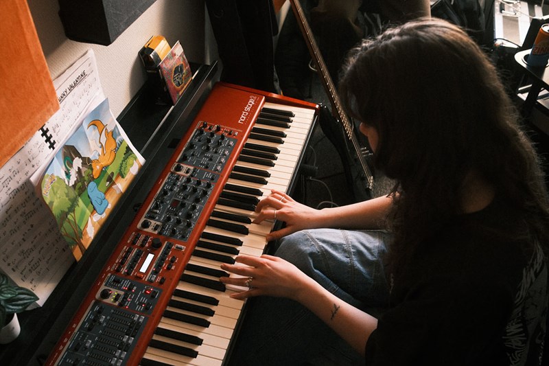 En person sitter och spelar på en keyboard.