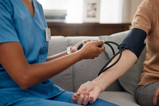 En vårdgivare mäter blodtrycket på en äldre patient.