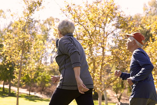 En äldre man och kvinna promenerar utomhus iklädda träningskläder