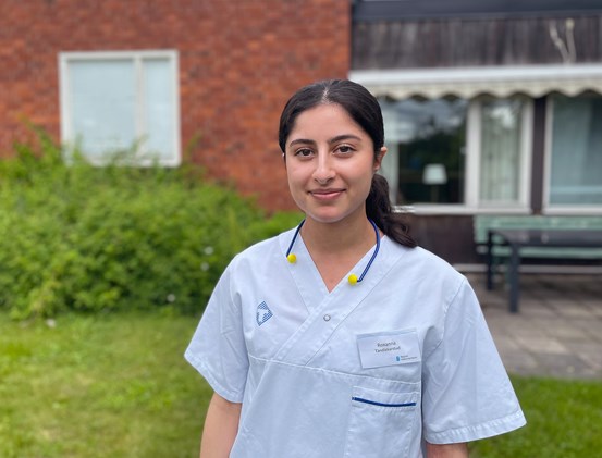 Tandläkarstudenten Roxanna Barghi i tandvårdskläder utomhus framför Folktandvården Kvissleby utanför Sundsvall.