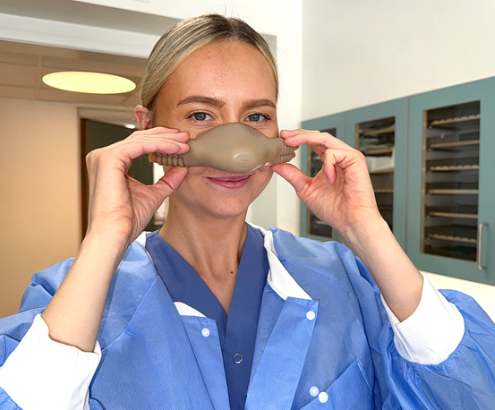 Tandläkare Ida Dahlgren visar hur en lustgasmask ska sitta över näsan.