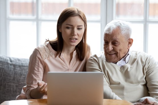 Kvinna och äldre man sitter framför en laptop